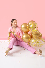 Wall Mural - Beautiful young woman with air balloons sitting on pink background