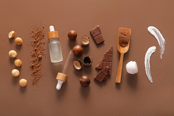 Wall Mural - Macadamia nuts, chocolate, cocoa, wooden scoop and bottle of cosmetic product on brown background