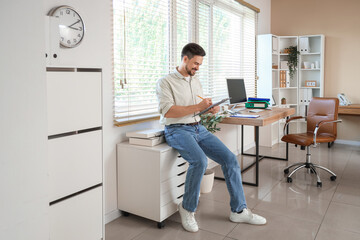 Canvas Print - Male accountant writing on clipboard in office