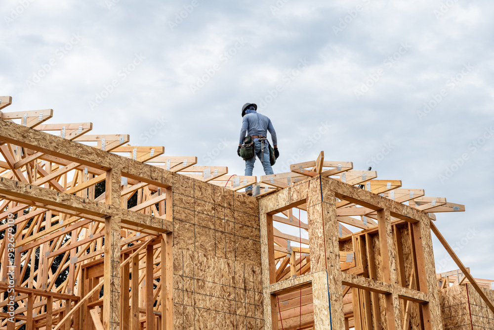 New residential home construction in framing stage, workman with ...