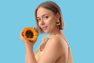 Sticker - Beautiful young happy woman with stylish makeup and sunflowers on blue background