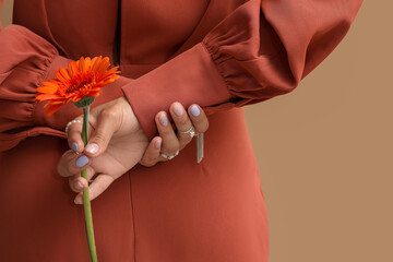 Wall Mural - Young woman with beautiful manicure holding gerbera flower on color background, closeup