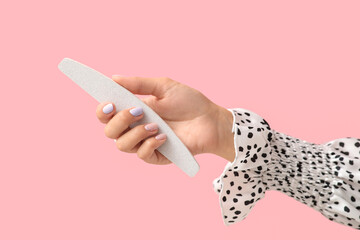 Wall Mural - Female hand with beautiful manicure and nail file on pink background, closeup