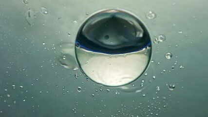 Wall Mural - Large transparent bubble is floating on a blue and green oily surface surrounded by smaller bubbles. The image evokes concepts like oil and water, chemistry, and science