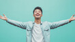 © Keitma - Young Asian man with open arms isolated on blue background , studio shot of an handsome Asian American guy with happy smiling face welcome with open arms on teal color backdrop