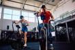 © Drazen - Couple of athletes exercising on stationary bikes in gym.