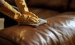 © TigerDude - The man in the cleaning gloves is cleaning the leather sofa with a microfiber cloth, in a close-up view of his hands and the furniture.