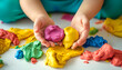 © Daniel - Colorful clay. Child's hands playing with colorful clay. Plasticine. play dough isolated with white highlights, 