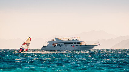 Poster - big boat and a surfer in the sea on the background of a rocky coast in Egypt Dahab