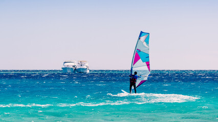 Poster - surfer rides in the Red Sea against the backdrop of two ships in Egypt Dahab