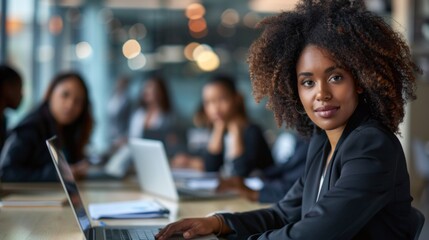 Poster - A confident woman collaborates with colleagues in a stylish office, focused on her laptop surrounded by a dynamic team