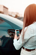 © Darius - A young woman charges a car at a charging station near a supermarket. Charging an electric car. Electric car concept. Vertical photo