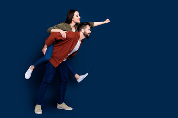 Profile side photo of cheerful crazy couple wear stylish clothes travel empty space isolated on dark blue color background