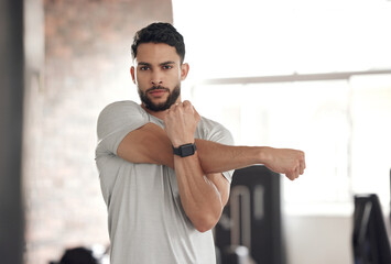 portrait, athlete and man in gym, stretching and serious for fitness with workout, warm up and welln