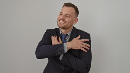 Poster - Young, confident hispanic man in suit hugging himself, smiling with happiness over isolated white background. positive expression of self-love, self-care, joy and egoism in business style attire.