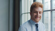 © Monkey Business - Head And Shoulders Portrait Of Smiling Young Businessman Standing By Window In Office