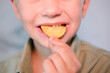 © Inna - Child puts snack in his mouth with his hand and enjoys eating fast food, potato chips. Offer of tasty and unhealthy food for children. Childhood obesity concept.