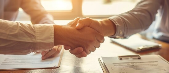 Wall Mural - Office desk, shaking hands over documents, business teamwork, close-up necks, cinematic light, copy space.