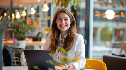 Fototapete - Smiling woman working on laptop in modern office setting.