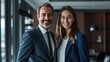 © hassan - Portrait of a business man and woman smiling in sleek office, standing side by side.