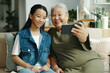 © DragonImages - Grandma taking selfie on mobile phone together with her granddaughter at home