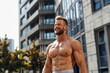 © Ирина Курмаева - A happy man without a t-shirt, showing his pumped-up torso, in front of a city building. A healthy way of life