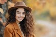 © olegganko - Young woman smiling in a brown hat and coat among autumn leaves in a park