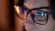 © wedmoments.stock - Close-up of a developer wearing glasses, coding on a computer. Code and analytics reflections in the glasses emphasize focus on cybersecurity and software development.