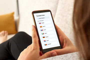 Close up photo of a girl on a sofa using language translator app with mobile smartphone.