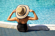 © Marharyta - Back view of woman in straw hat in pool in hotel. Summer holidays, enjoying summer vacations