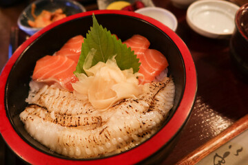 close up of Japanese raw seared salmon Flounder Sashimi fish rice in a black and red bowl donburi with ginger