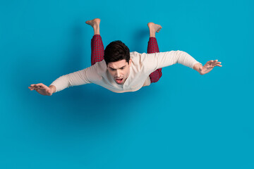 Sticker - Full length photo of handsome young guy falling down terrified dressed sleepwear sleepover good morning isolated on blue color background