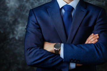 A man wearing a blue suit with crossed arms, represents confidence, power, and readiness for business and professional tasks.