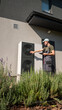 © StockMediaSeller - Technician adjusting a heat pump unit outside a house on a sunny day.