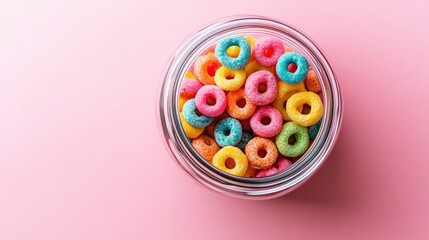 Wall Mural - A jar filled with colorful sweet cereal rings, photographed from above on a pink background, offering a cheerful and vibrant breakfast visual.