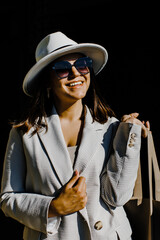 Beautiful brunette businesswoman wearing suit and white hat, walking on the street.