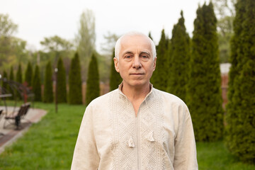 Wall Mural - Senior man outside on sunny day in nature wearing Ukrainian embroidered shirt. Independence day of Ukraine