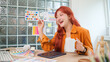 © wattana - Cheerful young graphic designer with red hair holding a coffee mug working at creative office.