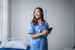 © Wasana - Happy young nurse using smartphone in hospital room