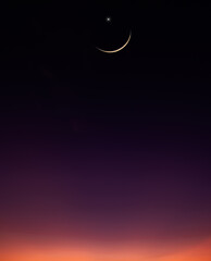 Wall Mural - dusk sky vertical in the evening with orange sunlight after sun down twilight and crescent moon symb