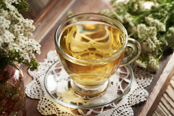 Wall Mural - Herbal tea in a transparent glass cup with fresh yarrow or Achillea millefolium flowers