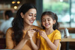 © Niks Ads - Indian mother and daughter eating chocolate in a restaurant, with a happy expression on their faces
