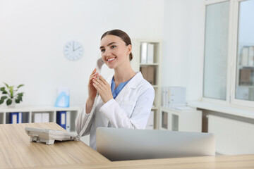 Sticker - Professional receptionist talking on phone at wooden desk in hospital