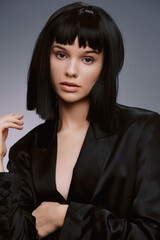 Woman, black suit, short bob hairstyle a woman in a sleek black suit stands confidently with her hands on her hips, gazing off to the side, her hair styled in an elegant short bob