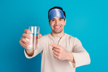 Sticker - Portrait of nice young man point finger water glass wear pajama isolated on blue color background