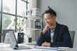 © amnaj - Accountant is smiling while working on his tablet and analyzing graphs and charts in his office