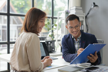 Wall Mural - Businessman holding clipboard and smiling while having a meeting with his colleague at the office