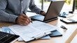 © Luluraschi - close-up hands using a calculator and notepad to manage a personal budget