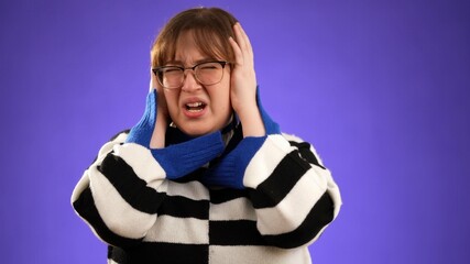 Displeased irritated frustrated sad angry young brunette woman 20s years old wears glasses, closed eyes cover ears do not want to listen scream isolated on purple background studio portrait