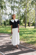 © Andrey Cherkasov - young girl in white blouse and black skirt walks in green park she smiles and is happy